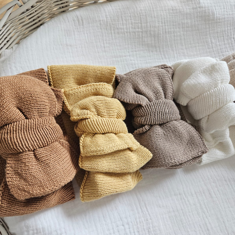 Assortment of knitted baby hats in multiple neutral tones by Little Raine Drops, displayed together to showcase available colours.