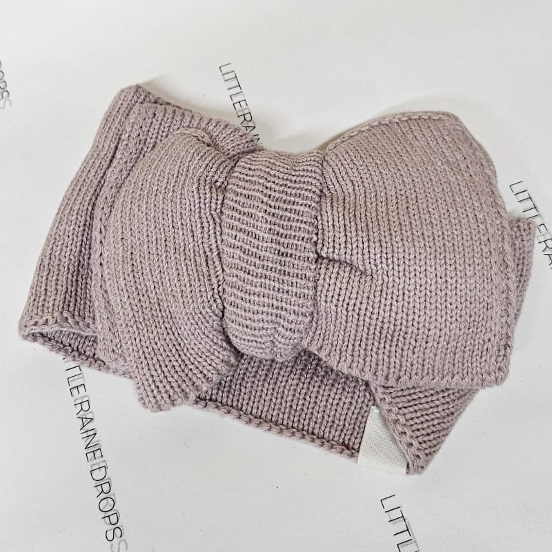Dusky lilac knitted bow headband for babies from Little Raine Drops, laid flat to highlight the soft ribbed knit and bow shape.