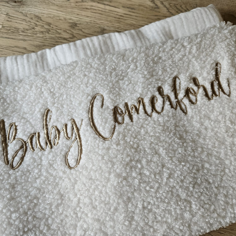Personalised cosy pearl boucle baby blanket embroidered with the name Baby Comerford, handmade keepsake by Little Raine Drops.