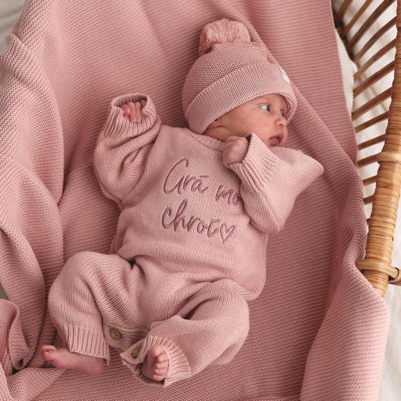 Dusky pink cotton knit personalised long-legged baby romper with embroidery, photographed on a dusky pink personalised cotton knit blanket