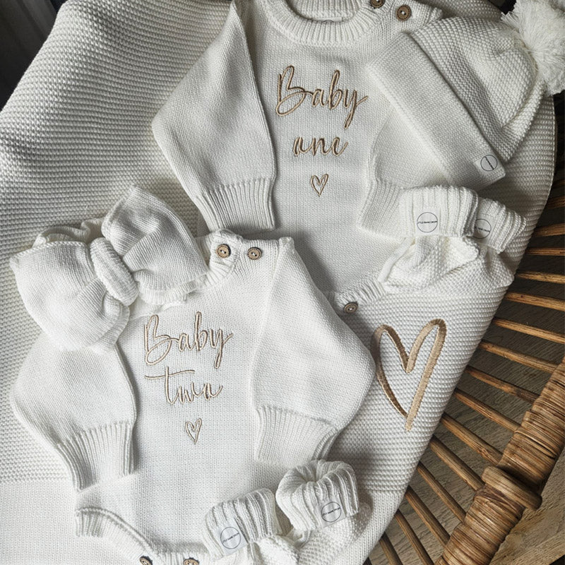 Coordinated pearl cotton knit baby announcement bundle including romper, hat, bow and booties. Personalised pearl cotton  knit blanket in background