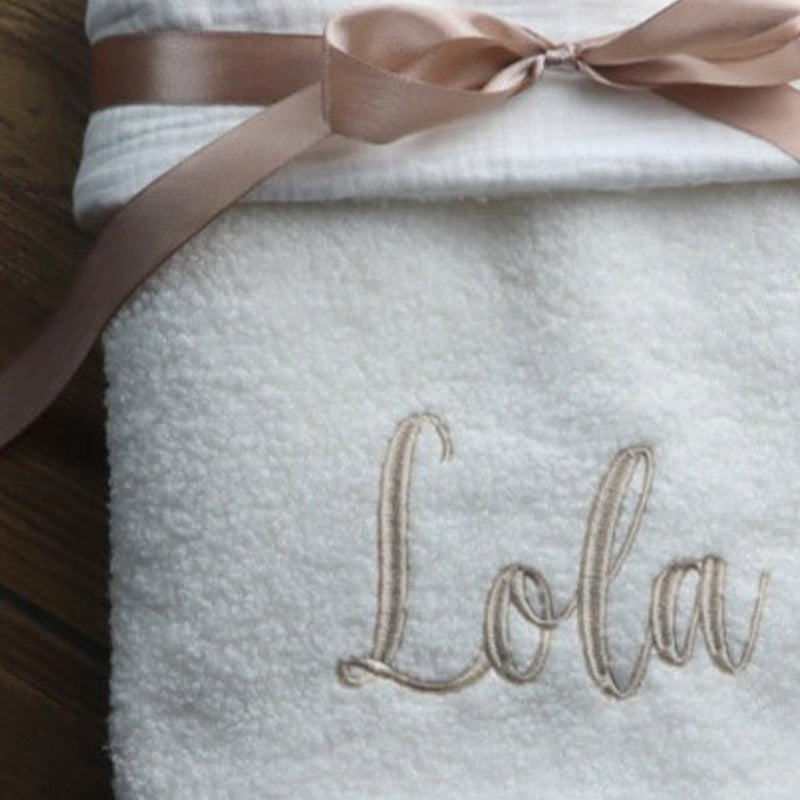 Close up of a cosy pearl boucle baby blanket tied with a soft ribbon and personalised name embroidery, luxury baby blanket by Little Raine Drops Ireland.