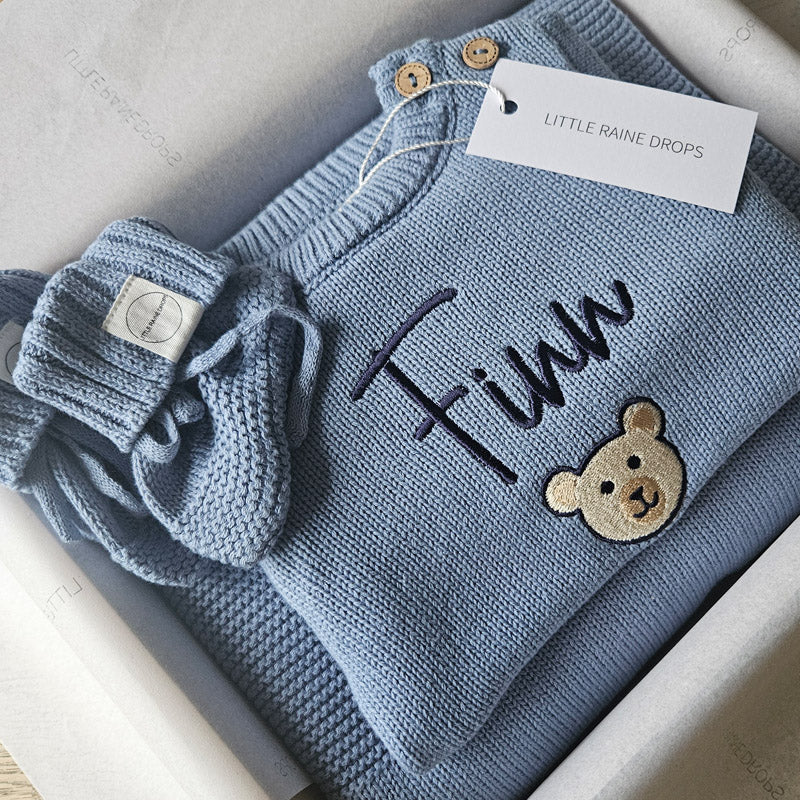 Dusky Blue personalised announcement set with personalised knit romper with the name Finn and picture of a teddy, matching personalised dusky blue blanket and booties, folded and boxed ready to be posted or gifted by Little Raine Drops