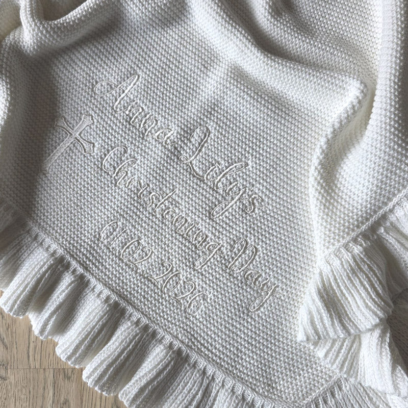 White cotton knit, scallop edge personalised christening blanket with child's name, and christening day, lying on wood background by Little Raine Drops Dublin