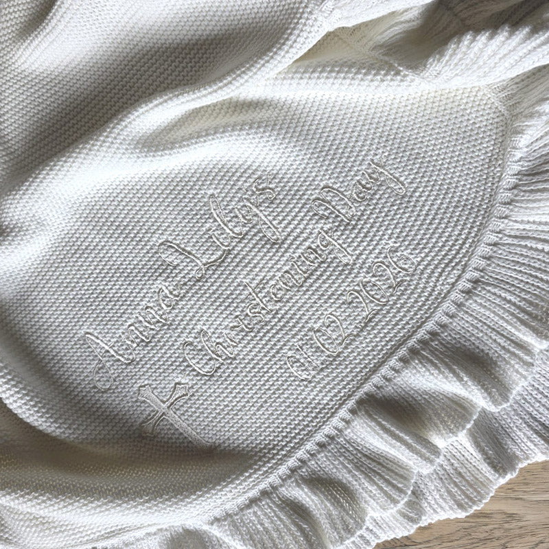 White cotton knit, scallop edge personalised christening blanket with child's name, and christening day, lying on wood background by Little Raine Drops Dublin
