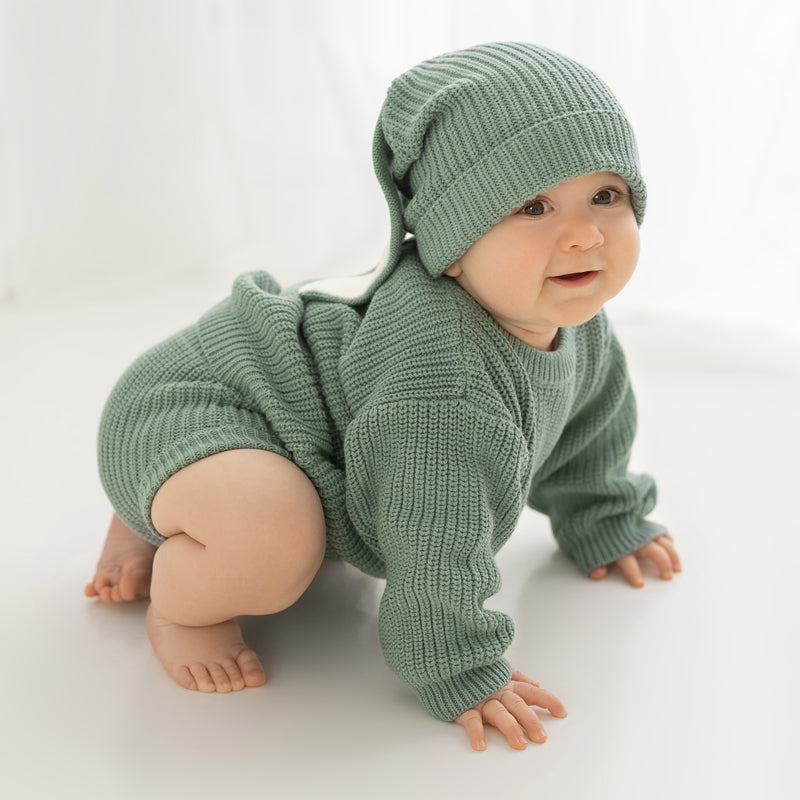 Baby wearing a sage chunky knit sweater with matching knit shorts and bunny beanie, styled on a clean white background. Soft cotton knit baby outfit designed for comfort, movement, and timeless everyday wear by Little Raine Drops.