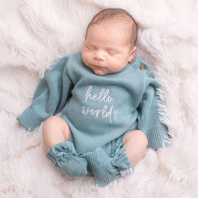 Newborn baby wearing sage green knitted announcement romper embroidered with hello world from Little Raine Drops Ireland