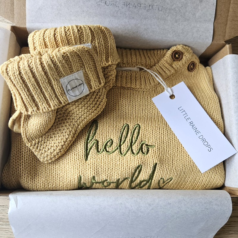 Ochre cotton knit baby romper and matching booties presented in gift packaging with Little Raine Drops tag, personalised newborn outfit set made in Ireland.