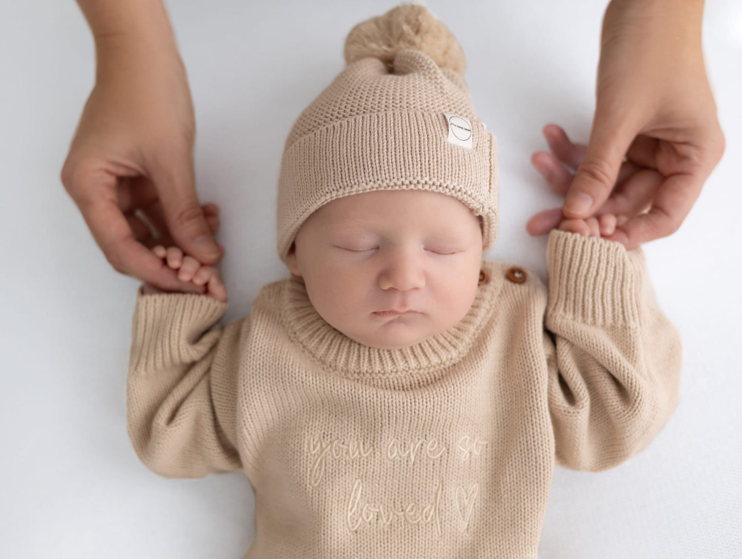 Baby asleep wearing personalised beige cotton knit romper, lying on a beige cotton knit personalised blanket with matching beige baby hat. Beautiful keepsake, announcement gift for newborn baby by Little Raine Drops Ireland